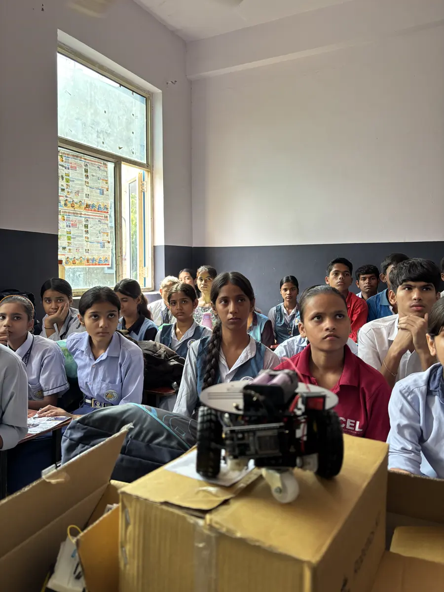 Students watching a robot car demonstration placed on a desk